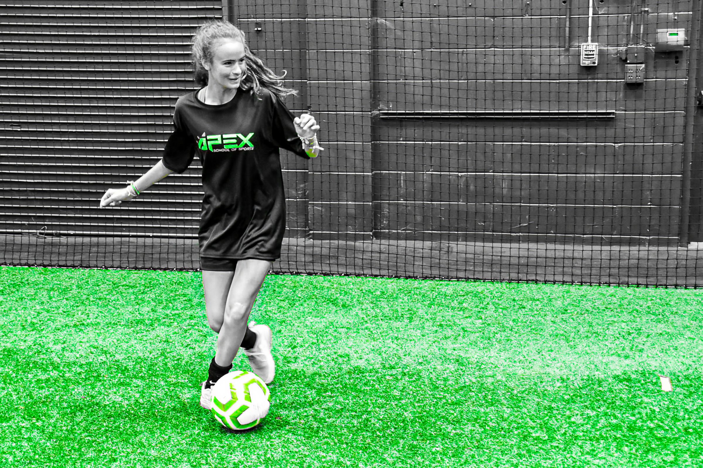 APEX soccer player dribbling on the turf