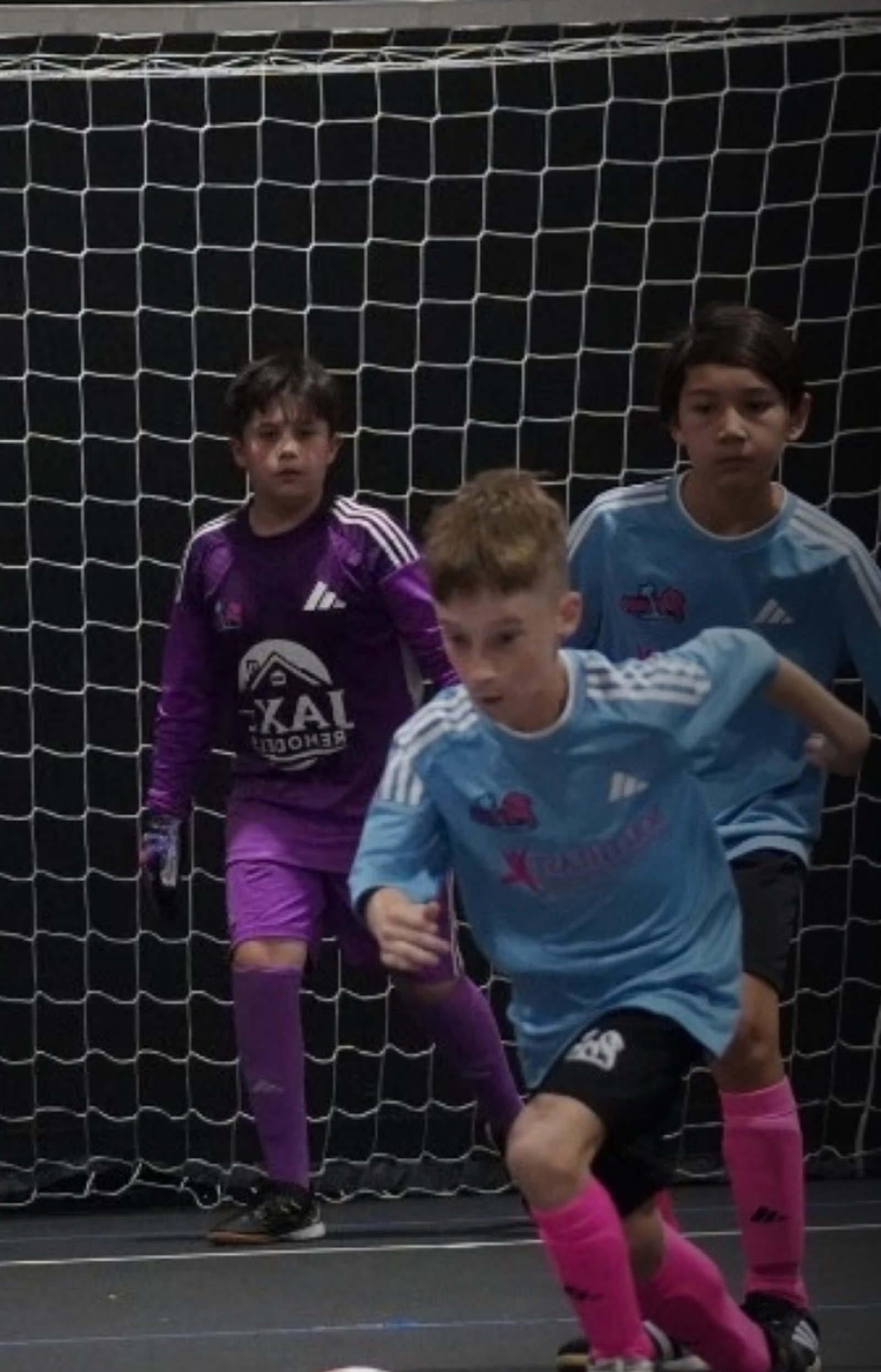 Young futsal player driving at goal